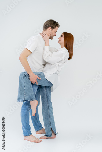 Side view of young couple looking at each other on white background.