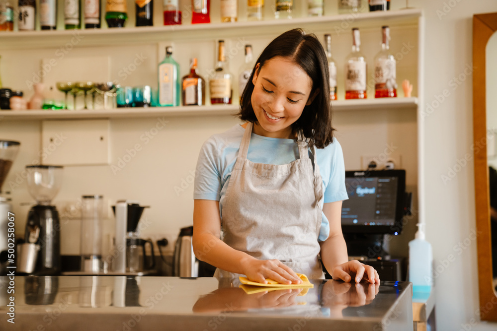 Young asian barista woman smiling while working in cafe