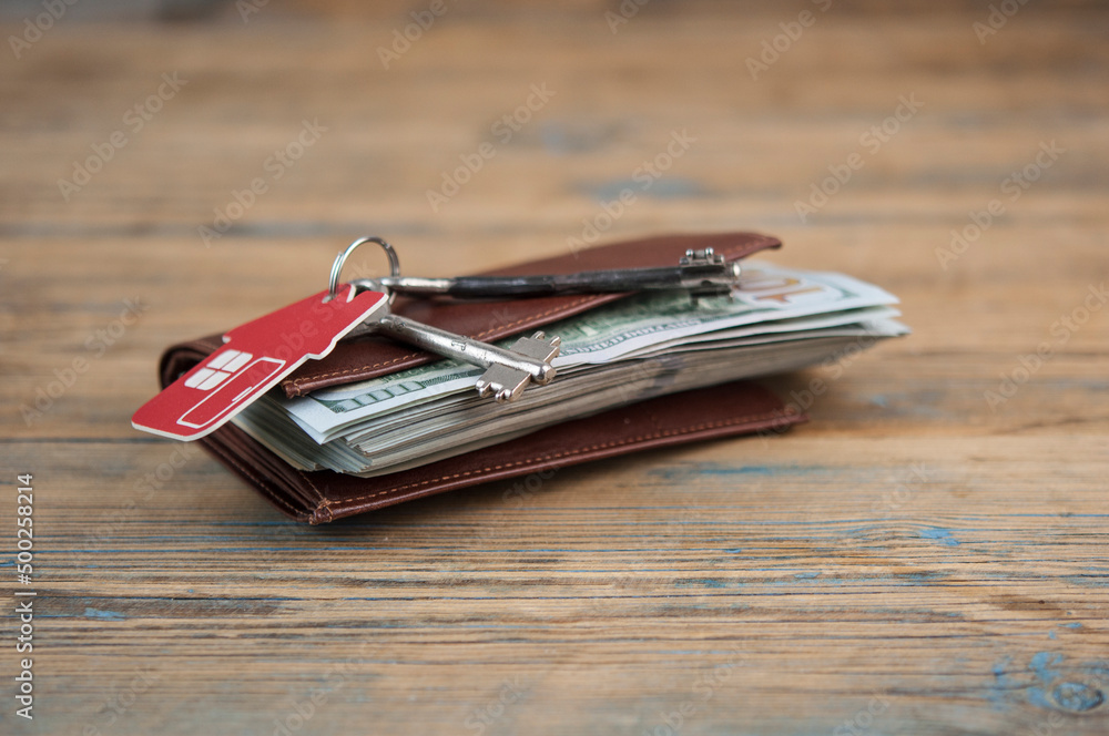 Brown leather wallet with one hundred dollar bills on wooden table. Top view Brown leather wallet with one hundred dollar bills on wooden table. Top view