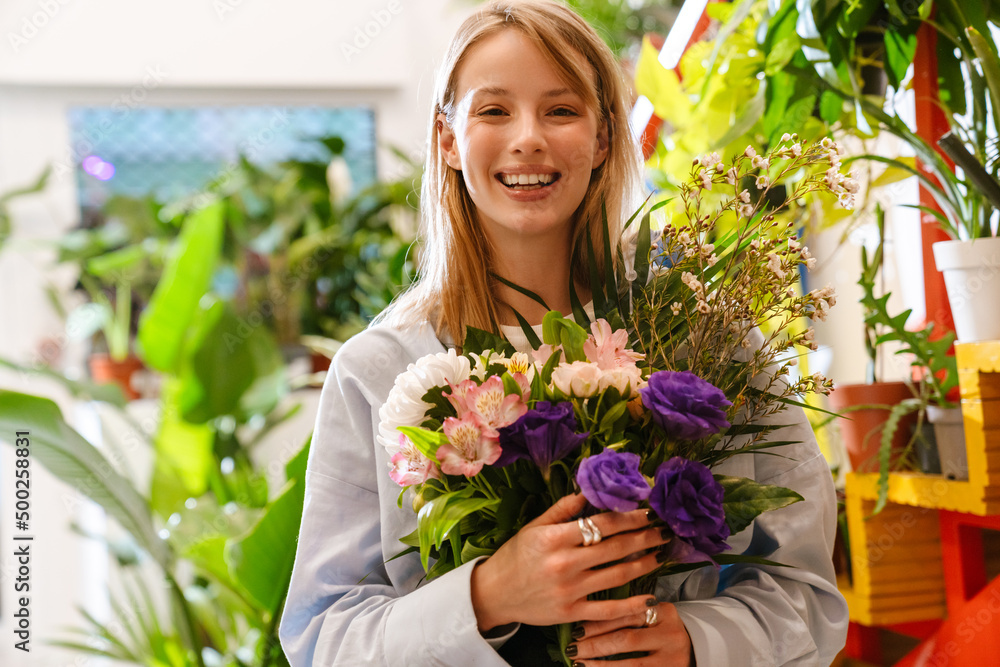 White beautiful florist girl holding bouquet with flowers in shop