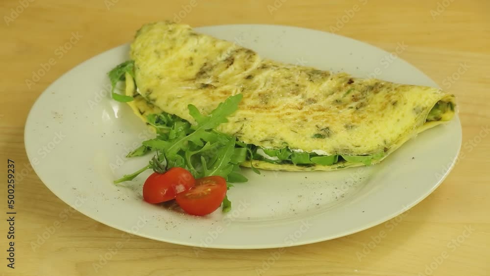 Omelet with herbs and tomatoes rotates on a wooden boards background Omelet with herbs and tomatoes rotates on a wooden boards background