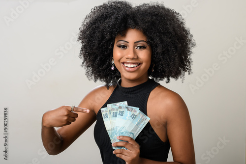 woman holding money, brazilian money, on gray background 