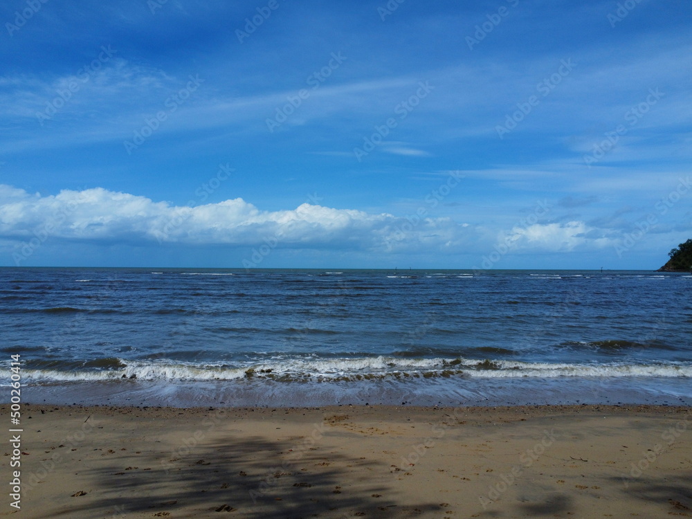 View of waves crashing onto beach with blue sky View of waves crashing onto beach with blue sky