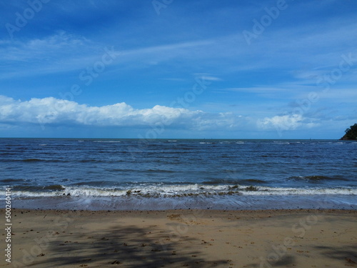 View of waves crashing onto beach with blue sky