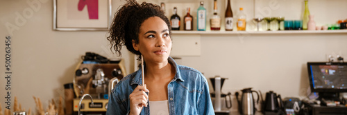 Black barista woman thinking and looking aside while working in cafe
