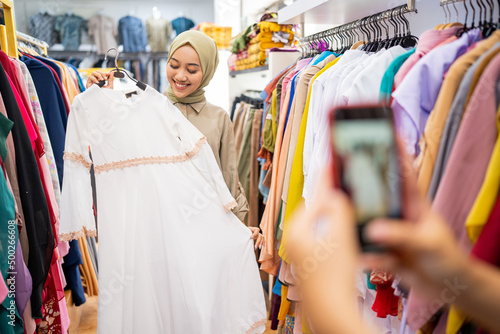 muslim woman taking picture of her friend while trying new clothes while shopping at the mall