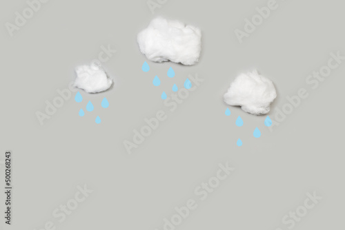 Nubes de algodón con gotas de lluvia sobre un fondo de cielo gris liso y aislado. Vista superior y de cerca. Copy space. Concepto: Meteorología
