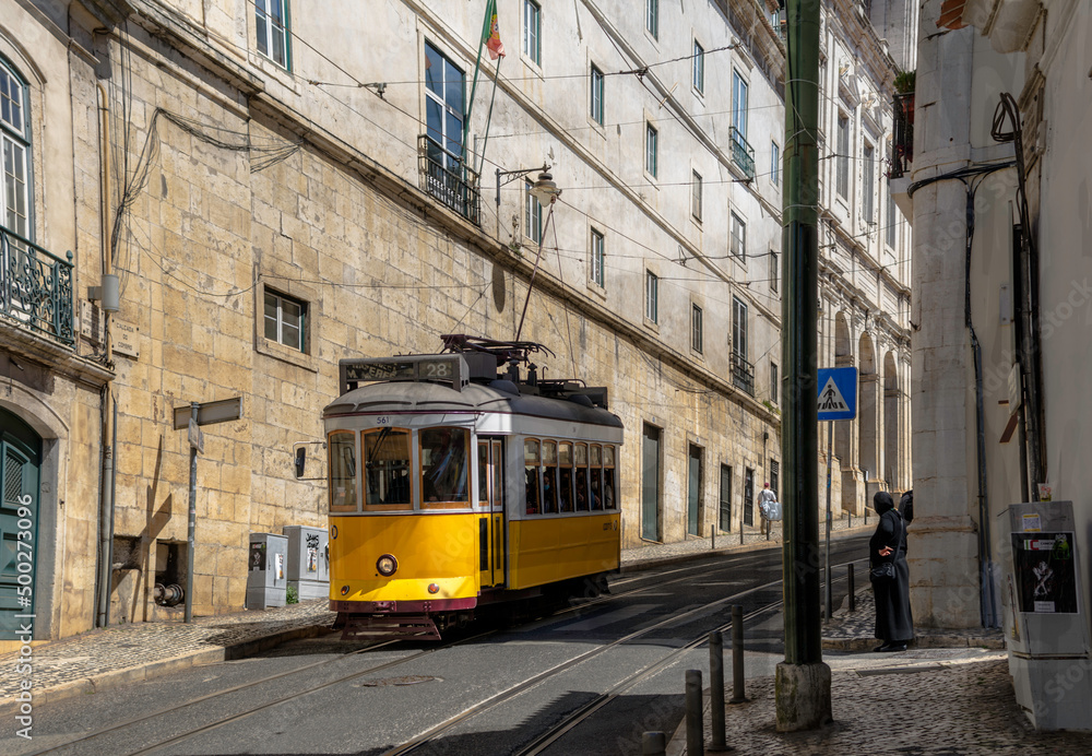 A typical vintage style public transport tram on the winding tracks in a street in Lisbon, Portugal.