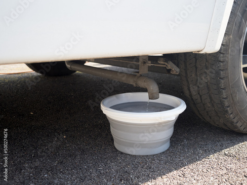 A collapsible bucket has ben placed under the waste pipe of a motorhome recreational vehicle to collect grey water from the onboard waste tank