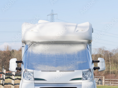 A motorhome recreational vehicle has a silver screen on its windscreen as protection from frost and condensation. Front view photo