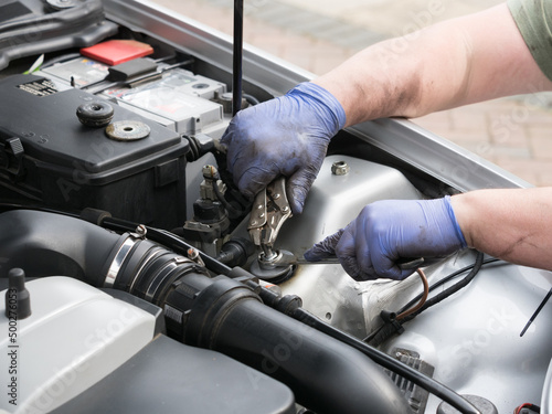 Canvas-taulu Pair of mechanic hands wearing blue gloves working in the engine bay of a sports