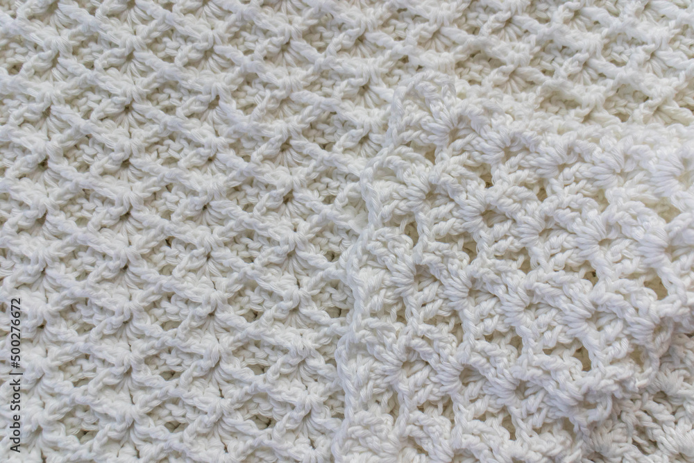 Close-up of a top view of a white cotton blanket with an original embossed crochet stitch pattern with a tip folded towards the center, handmade creativity Close-up of a top view of a white cotton blanket with an original embossed crochet stitch pattern with a tip folded towards the center, handmade creativity