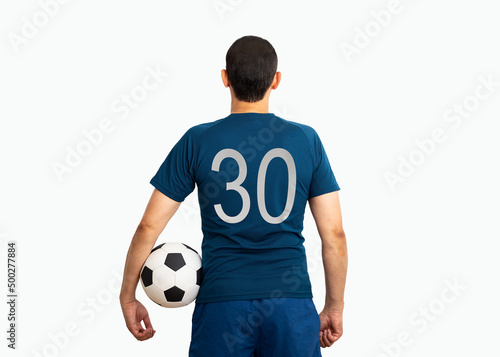 Cropped image and rear view of a young player with number thirty holding a soccer ball under his arms with white background