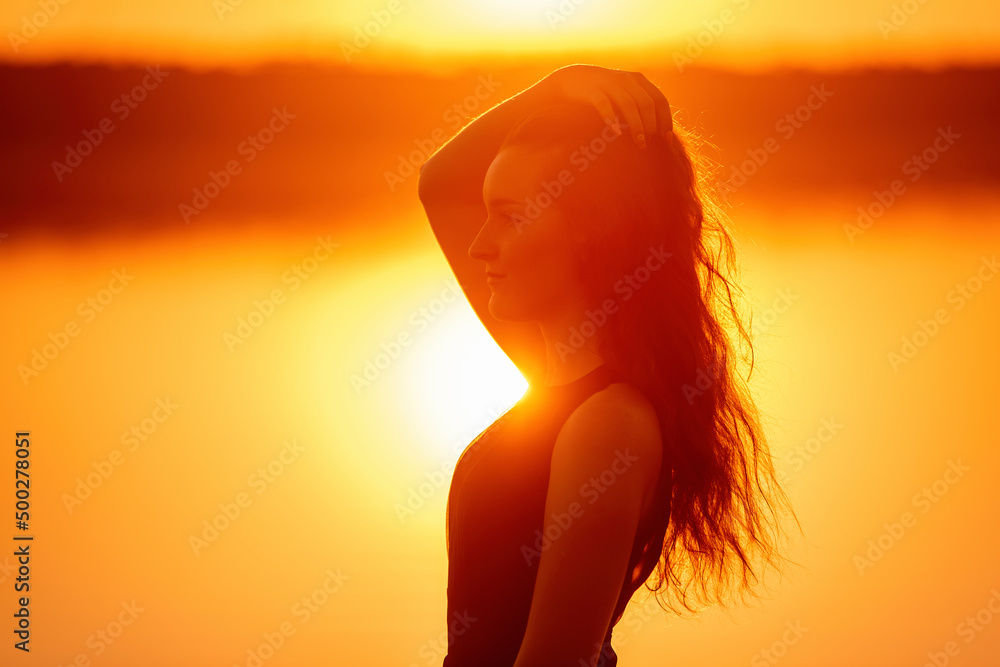Close-up portrait of silhouette of curly, free girl, wind in her hair, light movements at sunset