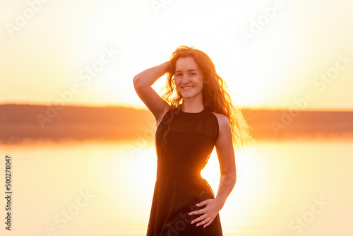 Close-up portrait of silhouette of curly, free girl, wind in her hair, light movements at sunset