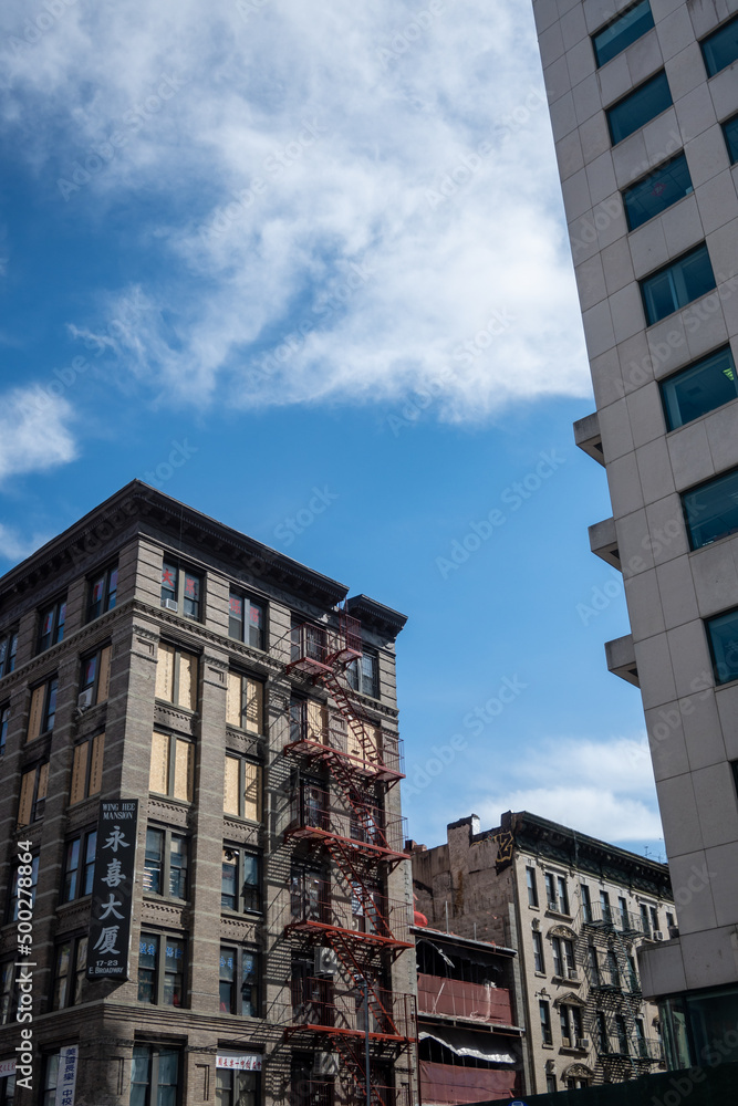 A New York City apartment building with a fire escape on a beautiful day