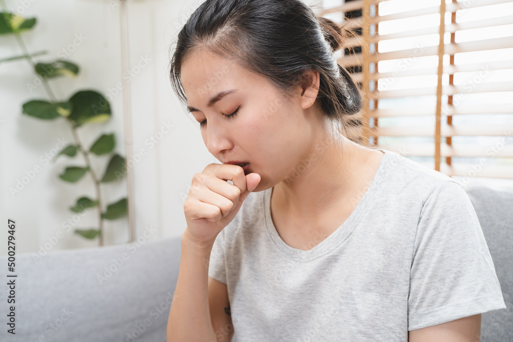 asian woman coughing and feeling sore throat at home. asian woman coughing and feeling sore throat at home.