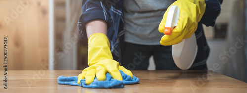 Asian woman cleaning the table surface with towel and spray detergent photo