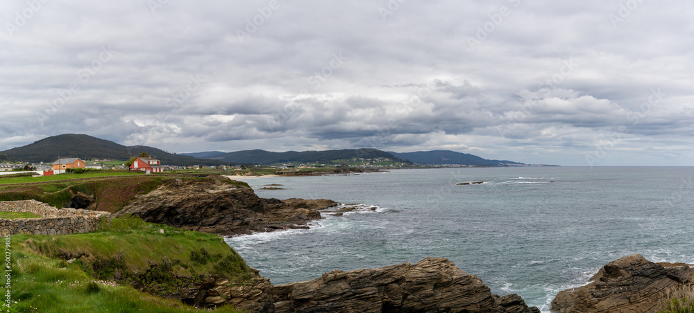coastline in Galicia near Foz with green meadows and homes on the seashore