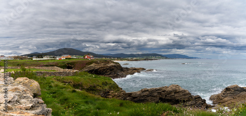 coastline in Galicia near Foz with green meadows and homes on the seashore