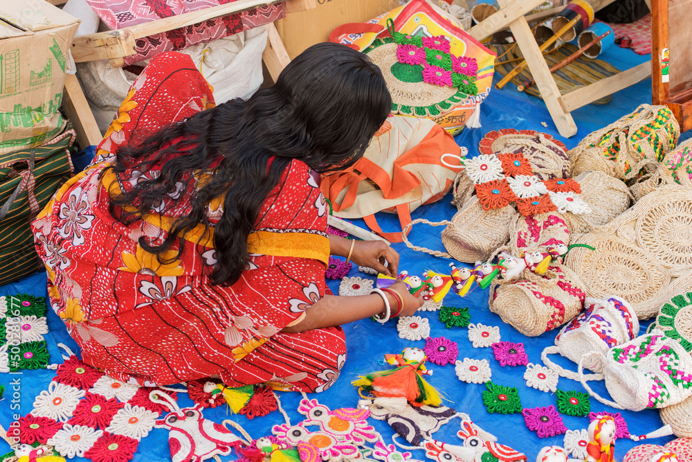 Fototapeta premium KOLKATA, WEST BENGAL , INDIA - NOVEMBER 23RD 2014 : Unidentified Indian woman making handmade jute dolls, handicrafts on during Handicraft Fair in Kolkata - the biggest handicrafts fair in Asia.