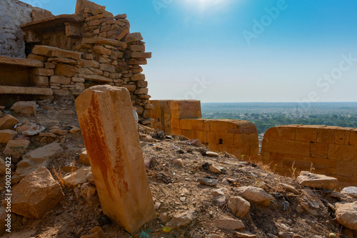 Jaisalmer, Rajasthan, India - October 13, 2019 : Great walls of Jaisalmer Fort or Sonar Quila or Golden Fort, made of yellow sandstone, in the morning light with city in the background. UNESCO site. photo