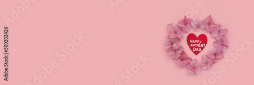 wooden red heart with white inscription happy mother's day and hydrangea petals on pink background photo