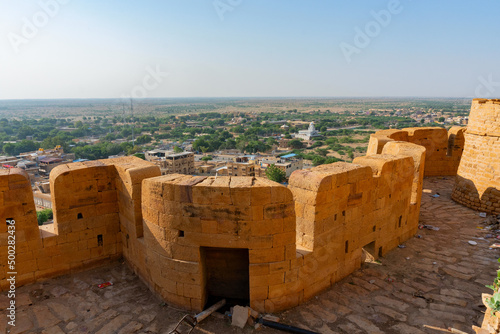 Jaisalmer, Rajasthan, India - October 13, 2019 : Great walls of Jaisalmer Fort or Sonar Quila or Golden Fort, made of yellow sandstone, in the morning light with city in the background. UNESCO site.