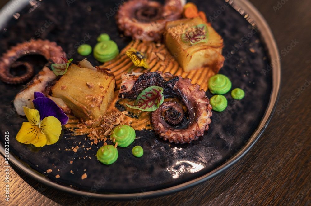 Octopus with potatoes on pea mash decorated with edible flowers Octopus with potatoes on pea mash decorated with edible flowers