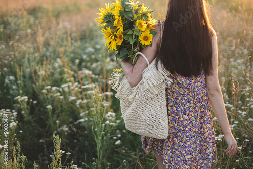 Foto Beautiful woman holding sunflowers in warm sunset light in meadow
