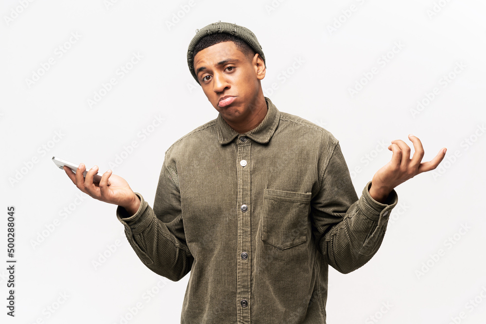 Attractive man wearing casual shirt holding smart phone in hands, spreading hans aside, dont know how to use application. Indoor studio shot isolated on white background Attractive man wearing casual shirt holding smart phone in hands, spreading hans aside, dont know how to use application. Indoor studio shot isolated on white background