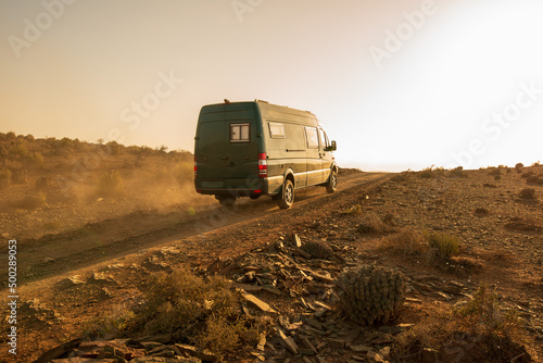 Fotografija 4x4 camper van going up a dusty road at sunset