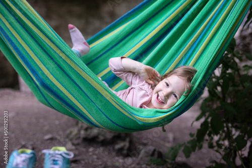Cute little girl laughing while lying in hammock