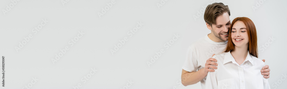 Cheerful man hugging girlfriend in shirt isolated on white, banner. Cheerful man hugging girlfriend in shirt isolated on white, banner.