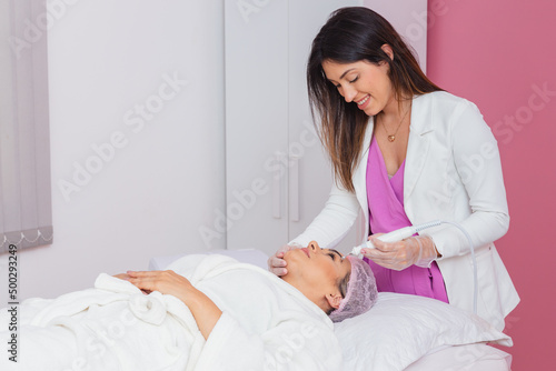 beautician doctor, woman applying facial plasma jet on patient, Application of aesthetic procedure, rejuvenation. photo