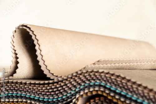 A catalog of different colors of fabrics in the hands of a girl for the choice of a client for upholstery, examples of multi-colored fabrics as a background, fabrics