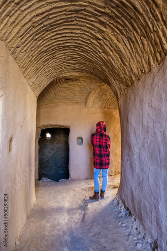 Woman admiring the ruins of the adobe village of Kharanaq in Iran photo