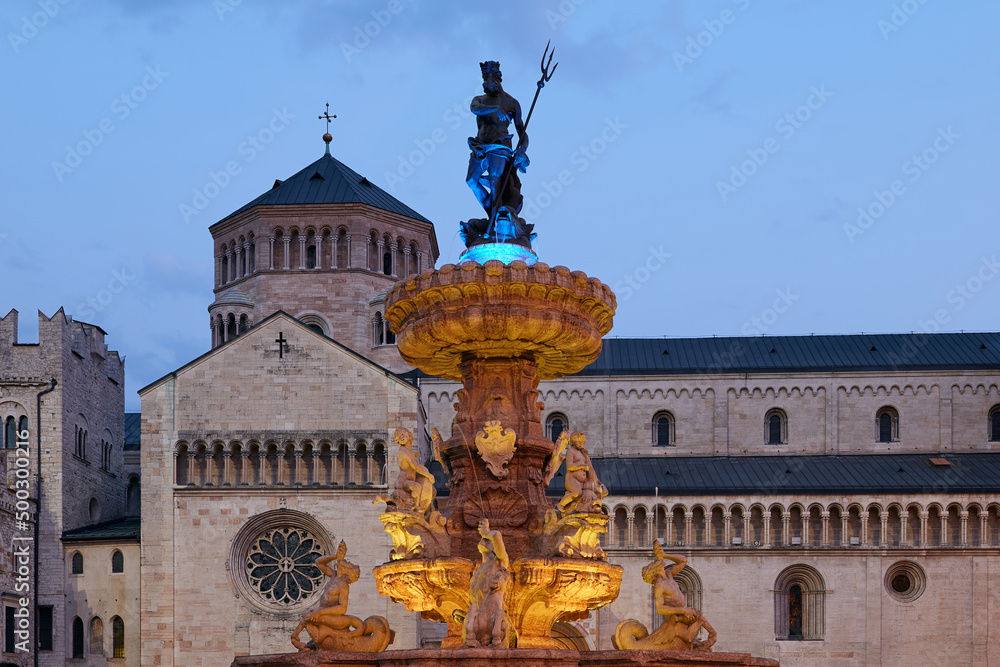 Illuminated Fountain of Neptune in the colors of the Ukrainian flag in front of Trento Cathedral in the Square Piazza Duomo in Trento, Italy
