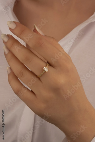 Beautiful lady's hand. woman wearing a white blouse and a diamond ring on her finger.