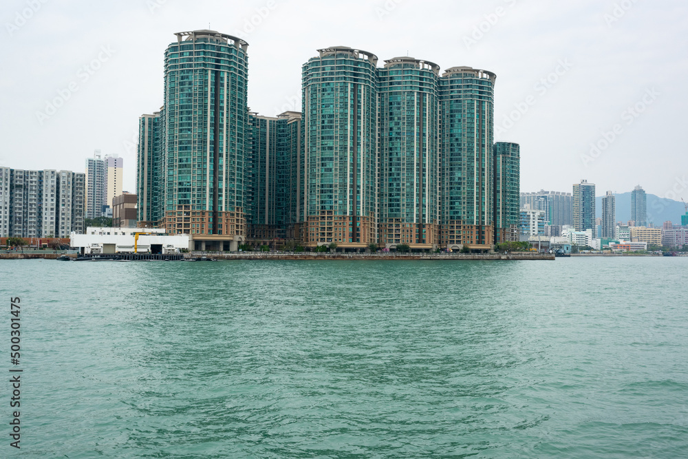 Group of green skyscrapers by the sea and Hong Kong city behind Group of green skyscrapers by the sea and Hong Kong city behind