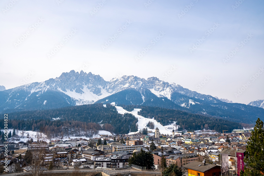 Scenic view of crowded houses in village. Beautiful townscape surrounded by snow covered mountain range. Holiday homes in south tyrol during winter.