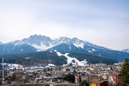 Scenic view of crowded houses in village. Beautiful townscape surrounded by snow covered mountain range. Holiday homes in south tyrol during winter. © Aerial Film Studio