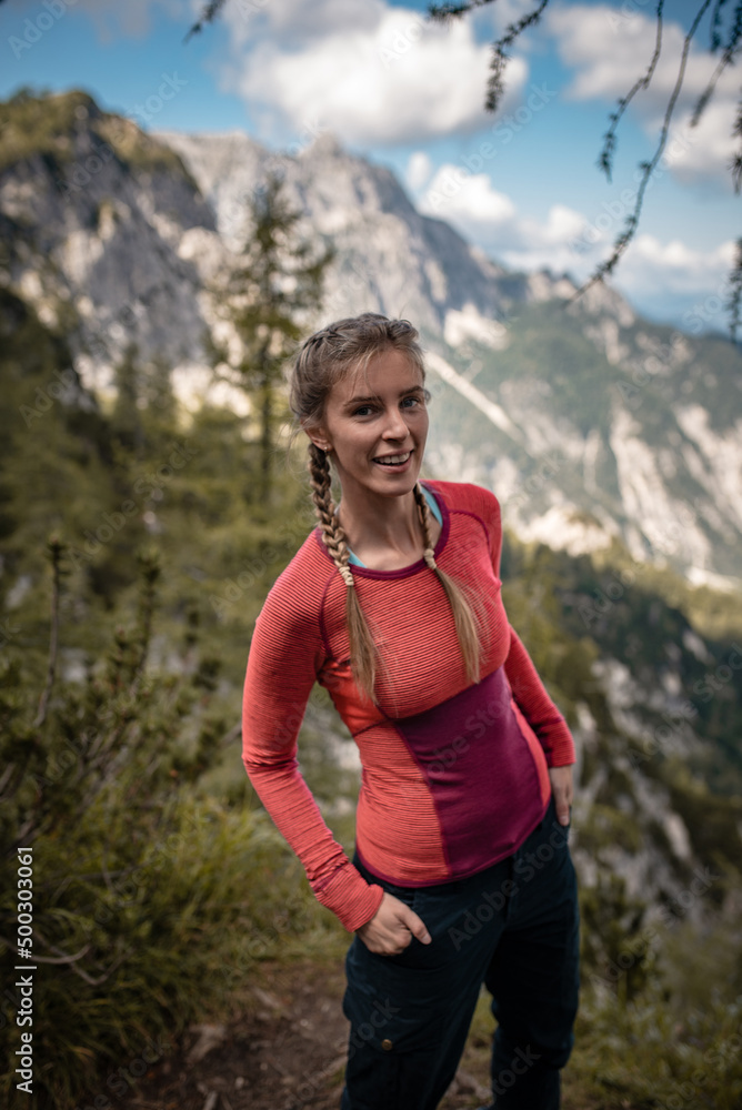 Young woman with braided hair is posing on a view point in Julian Alps during a September hike.