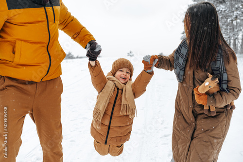 Happy family having a walk in winter outdoors in snow