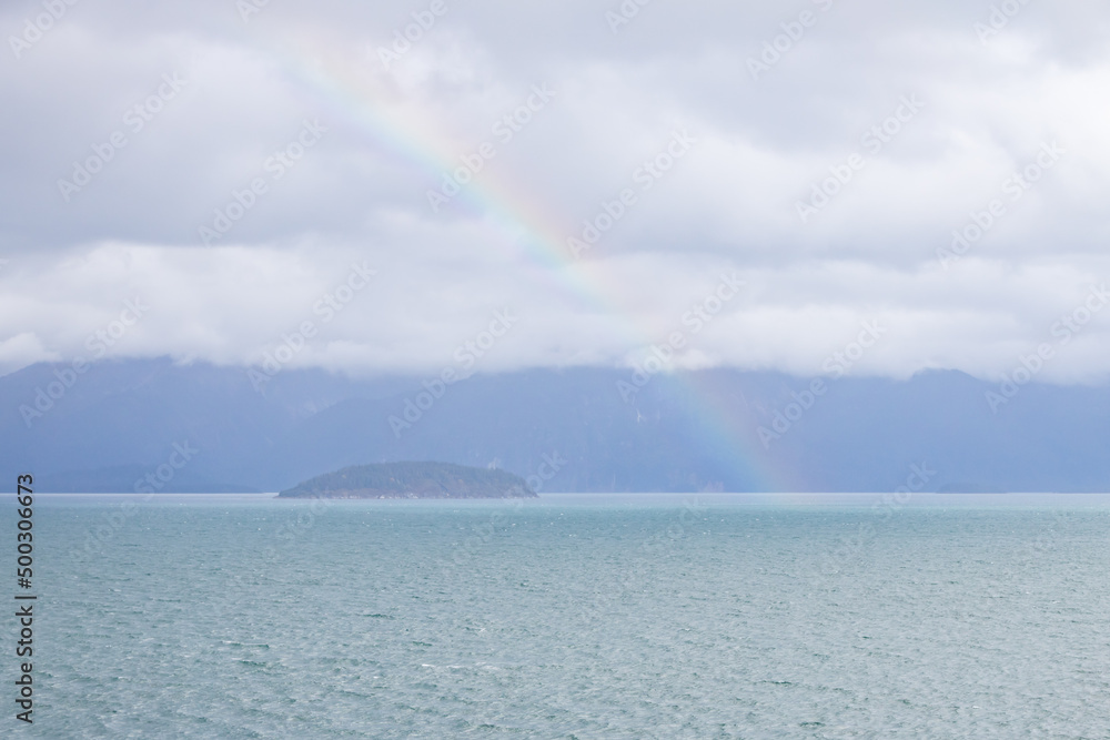 Storm clouds and rainbow over the ocean and island