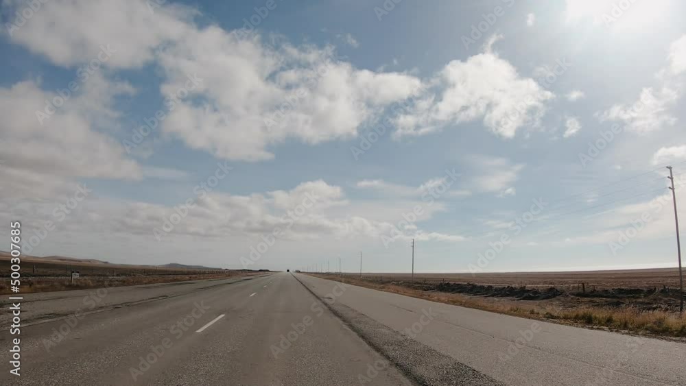 Journey. Point of view of a car driving along the rural road across the yellow grassland. View of the horizon and beautiful blue sky with clouds. Journey. Point of view of a car driving along the rural road across the yellow grassland. View of the horizon and beautiful blue sky with clouds.
