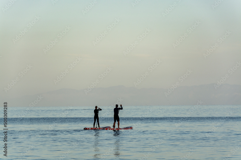 Silhouettes of people on paddle surf boards in Antlantic ocean on Tenerife island at sunset Silhouettes of people on paddle surf boards in Antlantic ocean on Tenerife island at sunset