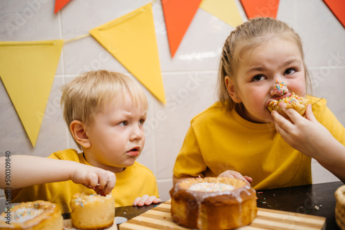  Portrait of two children eating homemade Easter sweets indoors