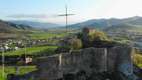 Aerial static view Kveshi fortress with with georgian flag and cross on top in spring. Historical and cultural heritage in Georgia photo
