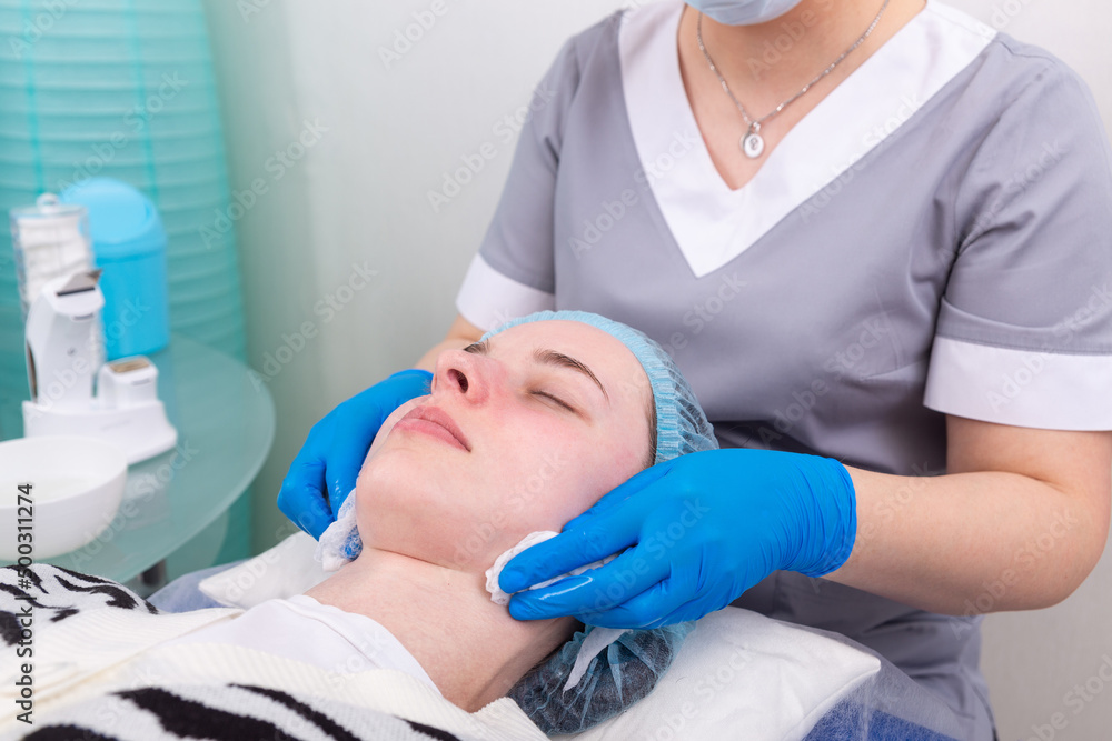 Obraz premium The cosmetologist treats the skin of the face with a tonic